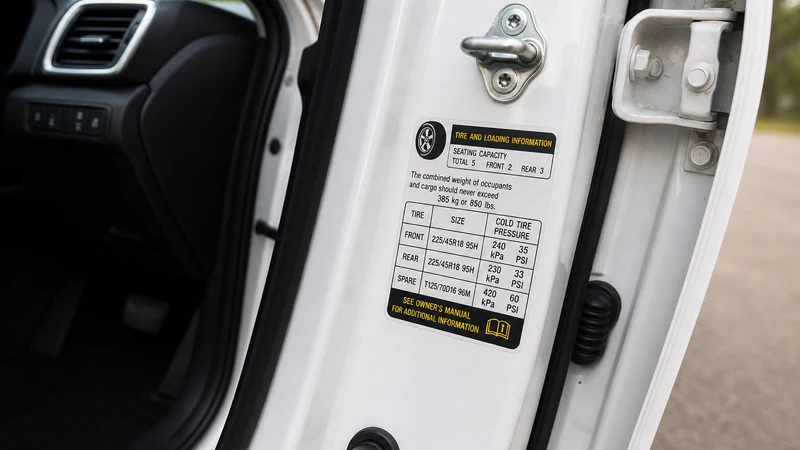 Close-up of a driver-side door jamb tire information sticker showing recommended PSI for front and rear tires