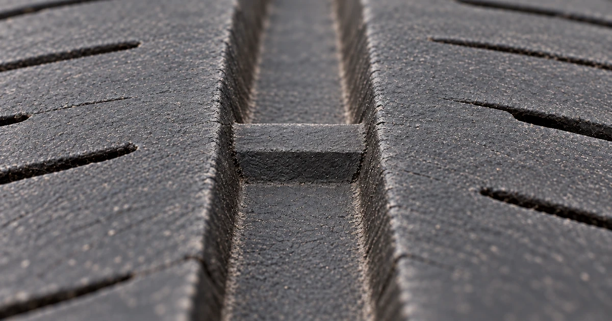 Close-up of a tire tread groove showing a raised rubber wear bar bridging the bottom of the groove