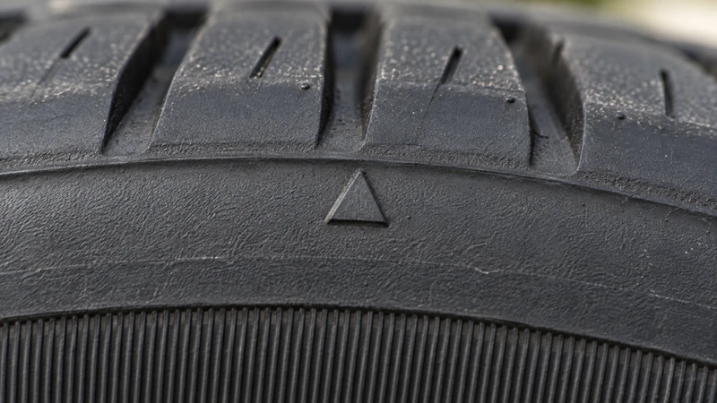 Close-up of a tire sidewall showing the small triangle TWI marker that points to wear bar locations in the tread