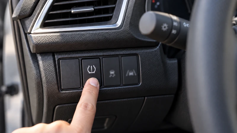 The physical TPMS reset button to the left of the steering column on older Honda models